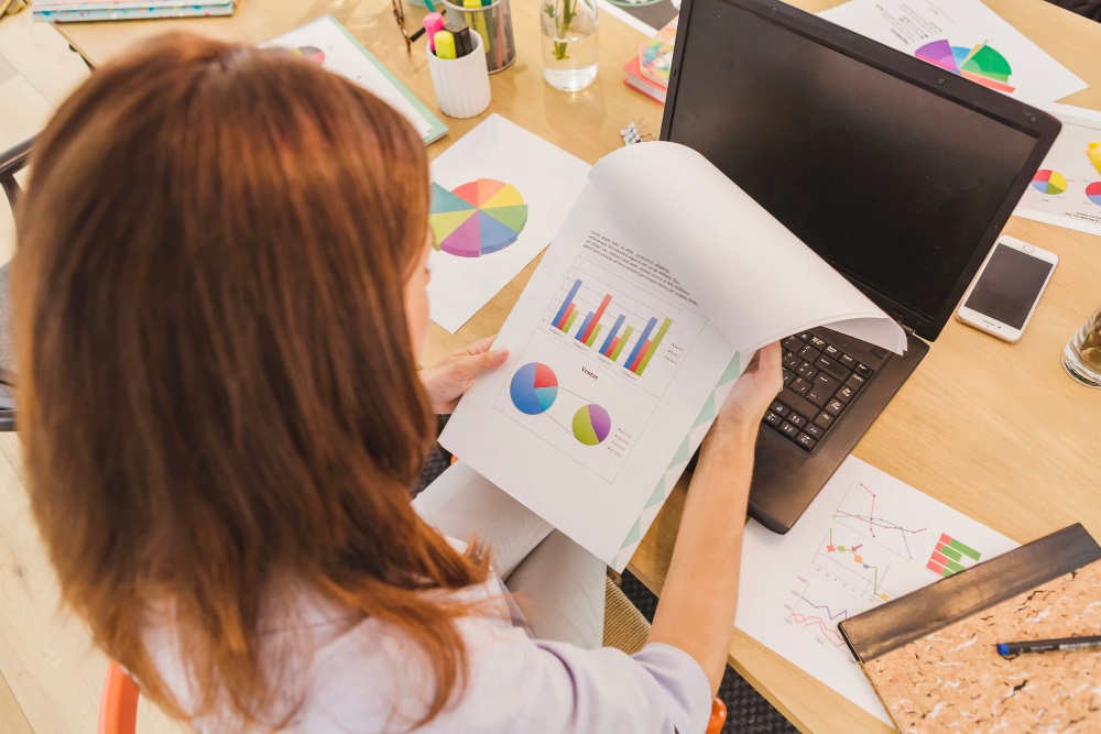 mujer con un documento entre las manos que contiene una gráfica con datos